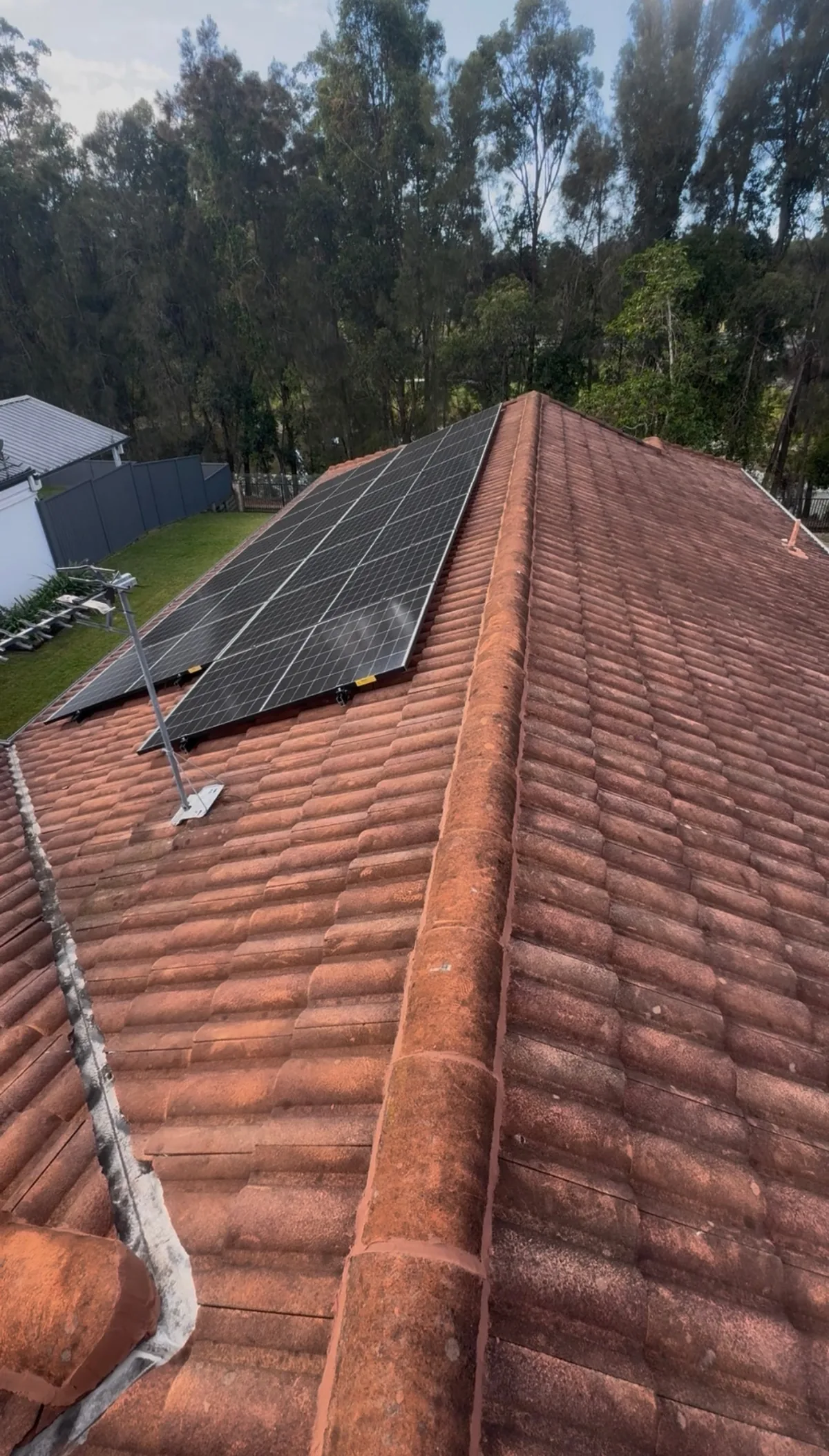 Terracotta tile roof and solar panels coated in dirt and lichen — before